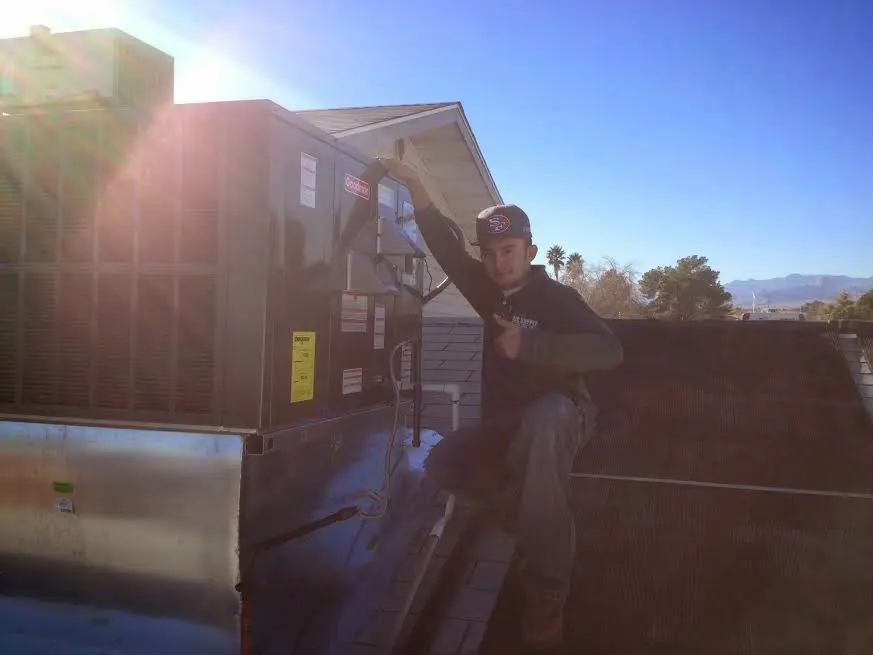 HVAC technician performing AC Tune-Up on a rooftop unit in Bolivar